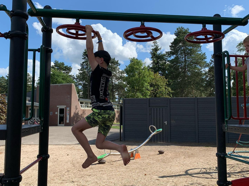 Hangen aan de wielladder van metalen speeltoestel met kunststof speelelementen