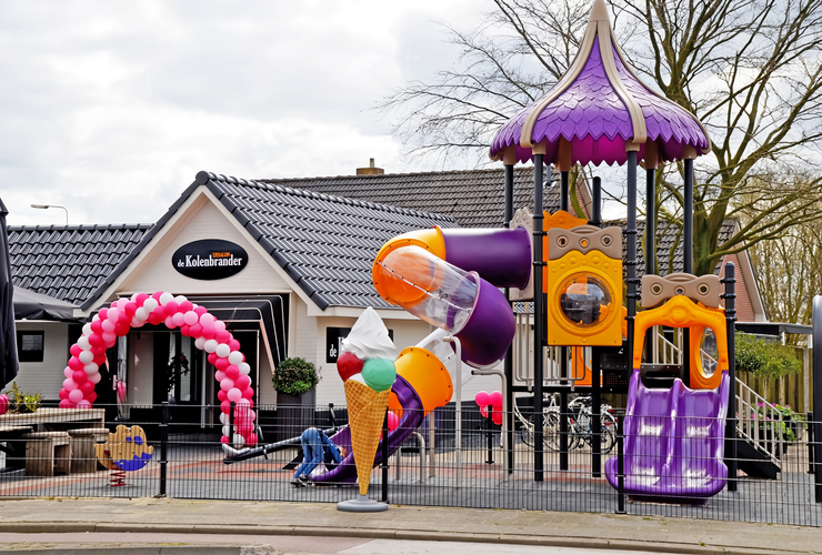 Paarse en gele speeltoren met glijbanen bij een recreatielocatie